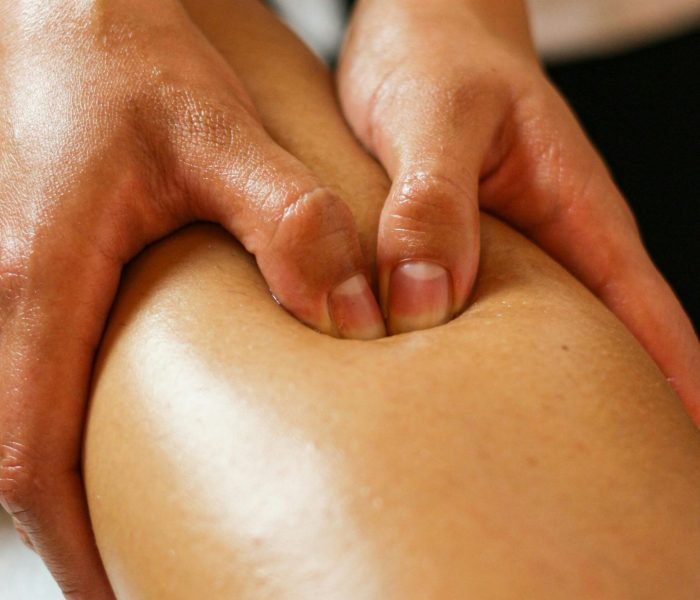 Close-up of hands applying pressure on a leg during a therapeutic massage session.